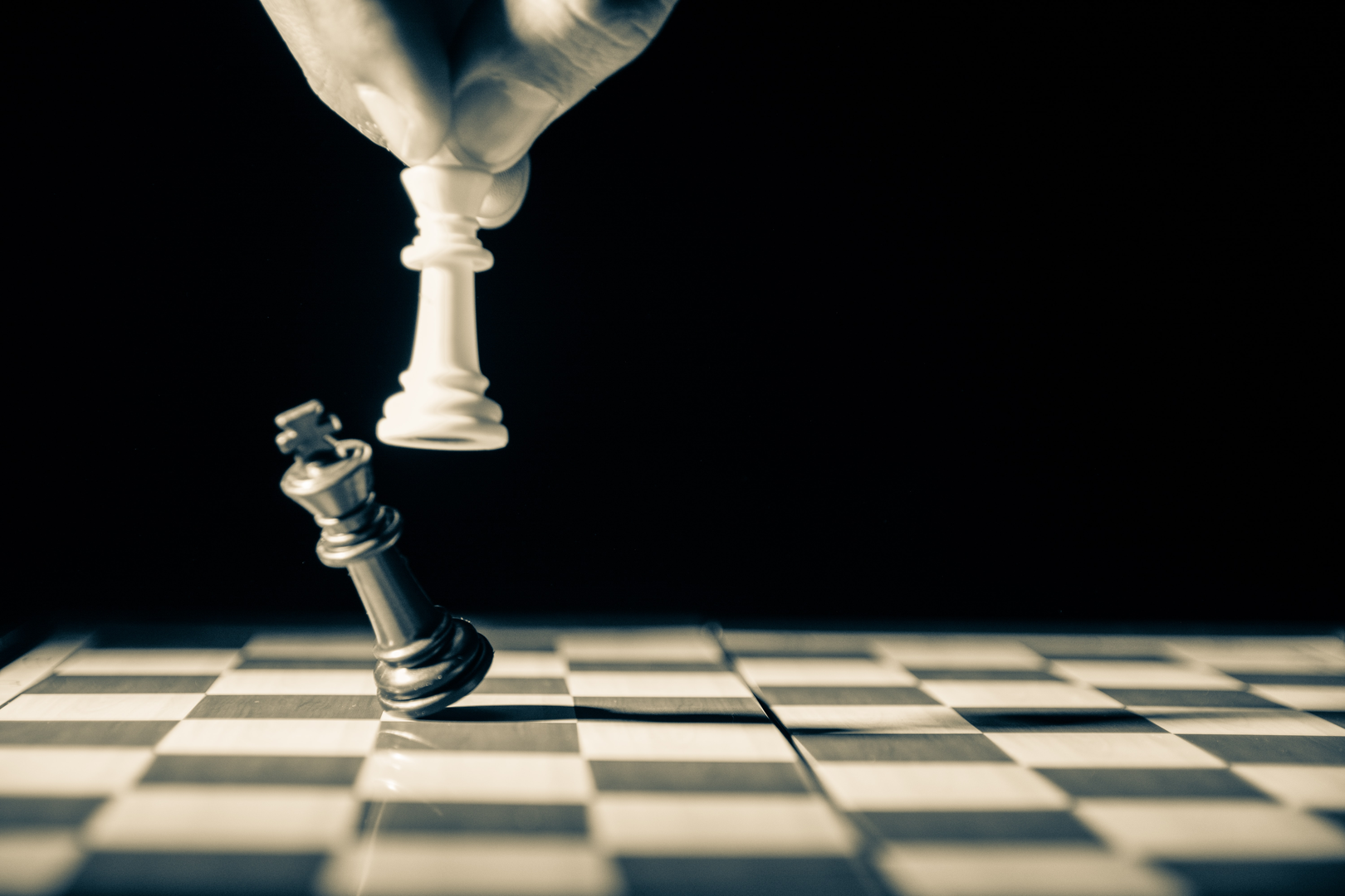 Close up of white king taking down black king. Hand and fingers and chess board with vintage look | © Unsplash / GR Stocks