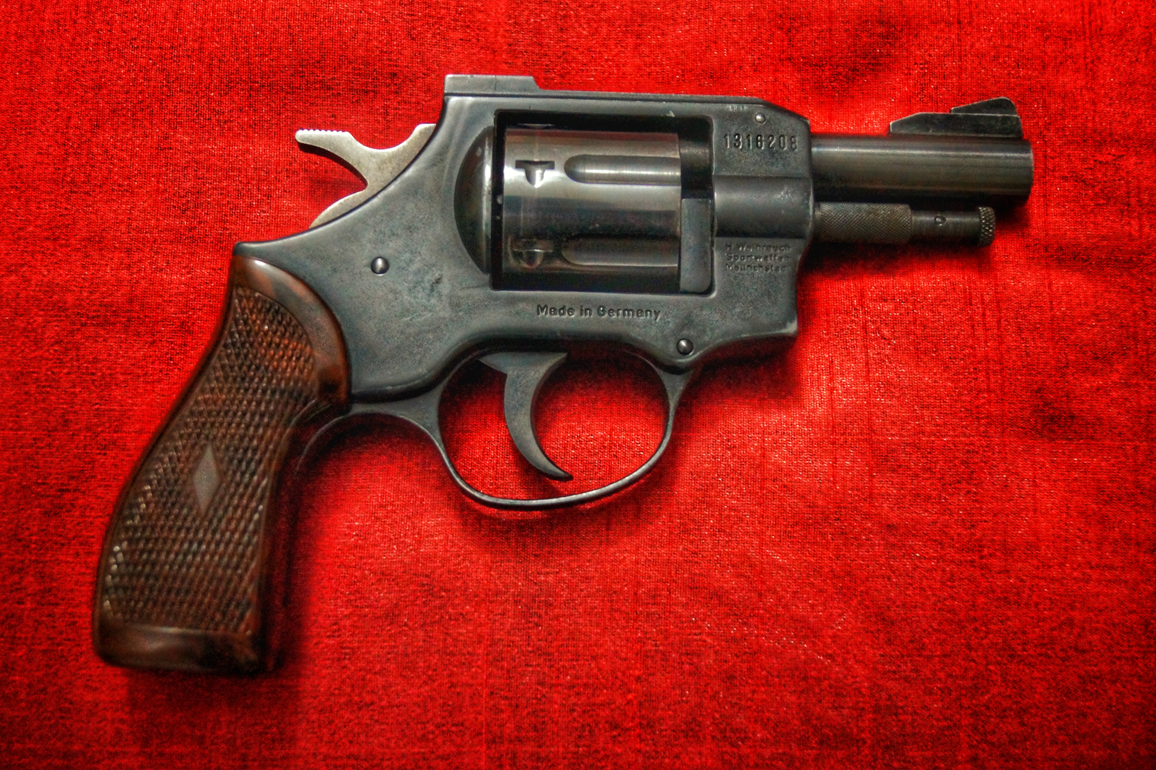 a vintage revolver with a red backdrop | © Unsplash / Arnav Singhal
