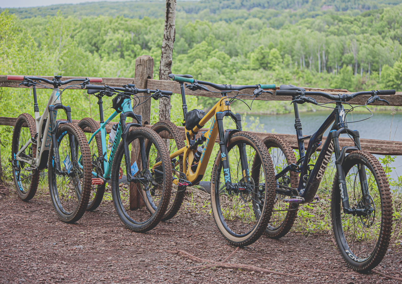 Mountain Bikes Leaning on a Wooden Fence overlooking lake and trees | © Unsplash / Tom Conway