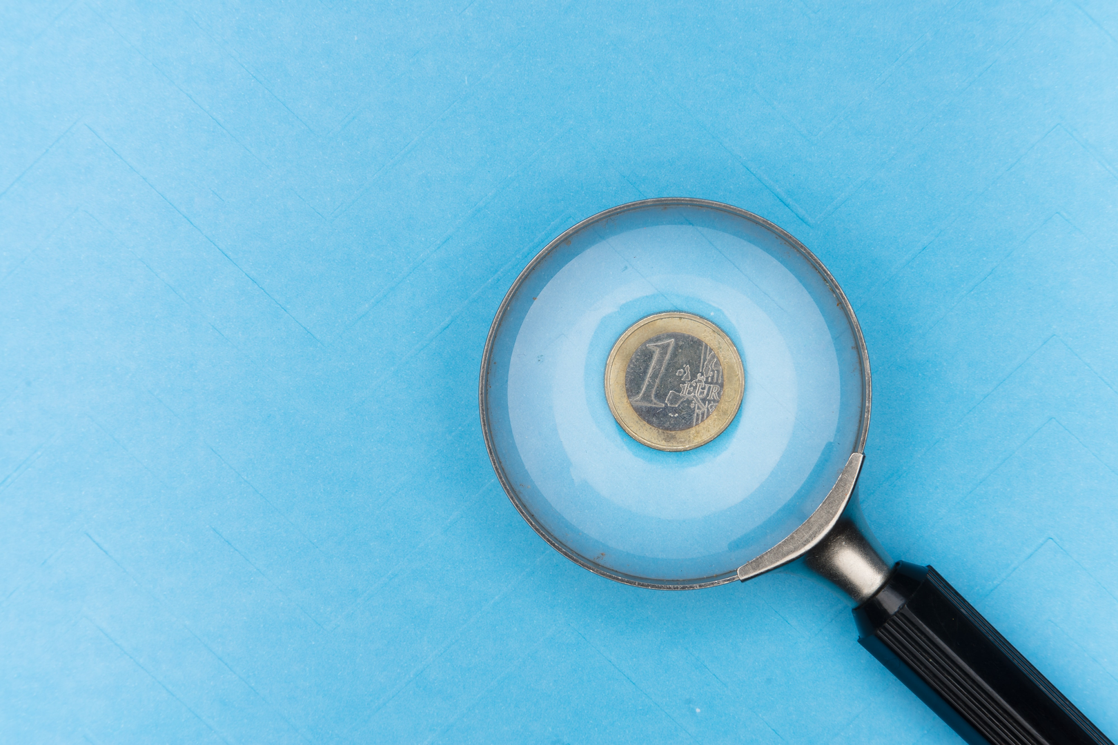 a euro coin under the magnifying glass | © Unsplash / Markus Winkler