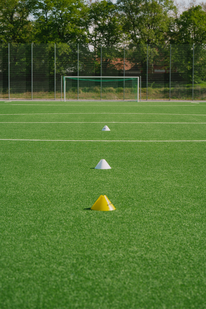 3 pylons on a soccer field, with a soccer goal in the background. ⚽️🥅 | © Unsplash / Max Zindel