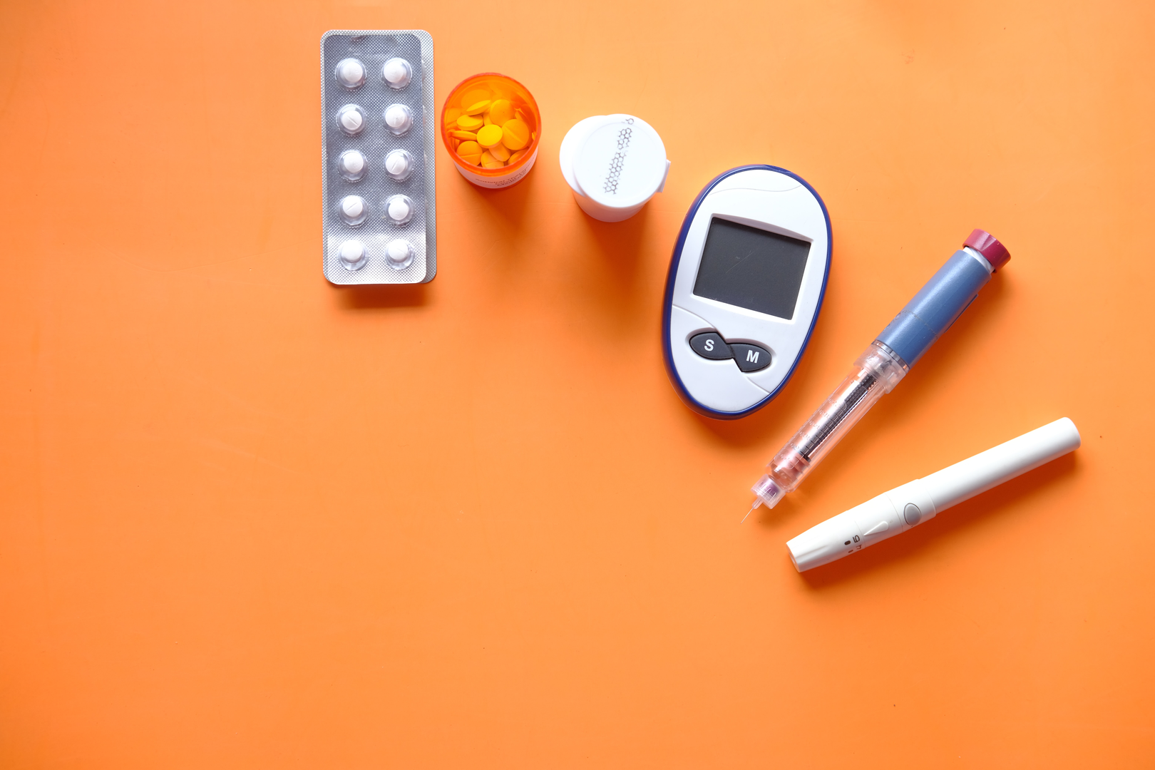 insulin pen, diabetic measurement tools and pills on orange background  | © Unsplash / Towfiqu barbhuiya