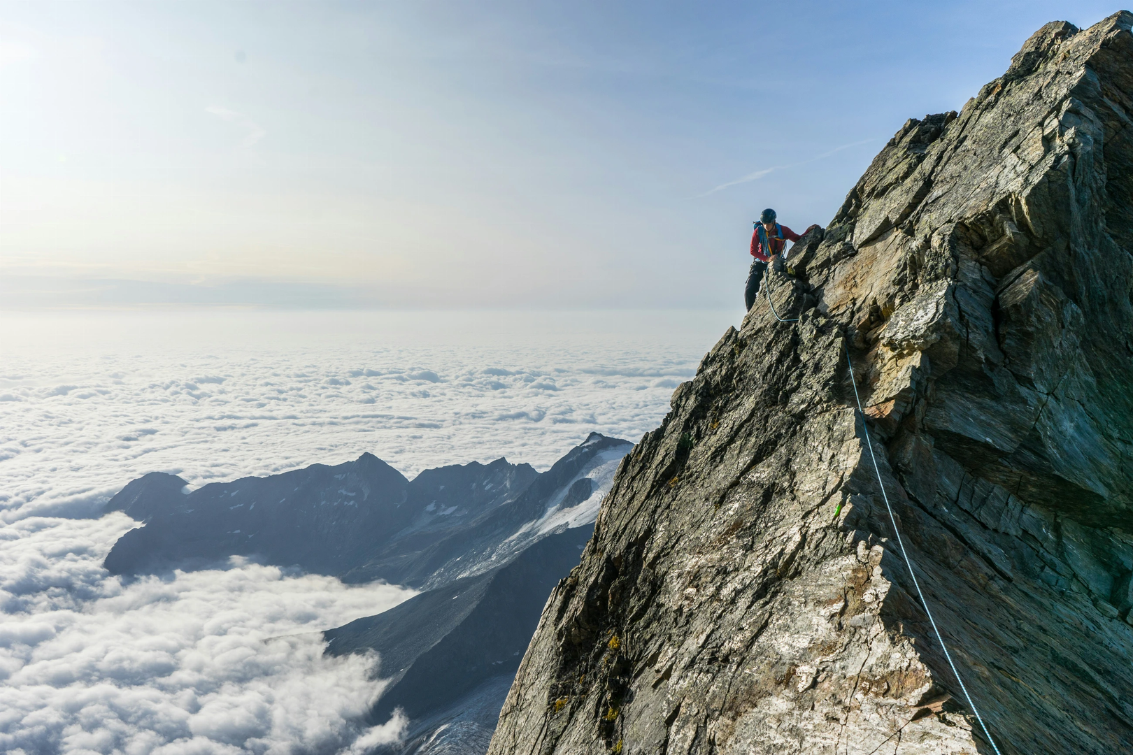 My brother traverses the ridge high on the Lagginhorn, with Italy hidden beneath the layer of clouds in the background. | © Unsplash / Jef Willemyns