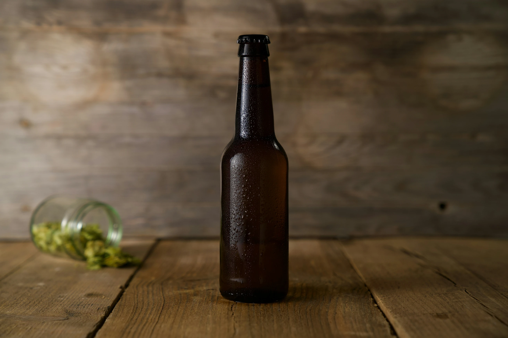 Beer bottle on a wooden table with spilt hops in the background. | © Unsplash / Story Ninety-Four