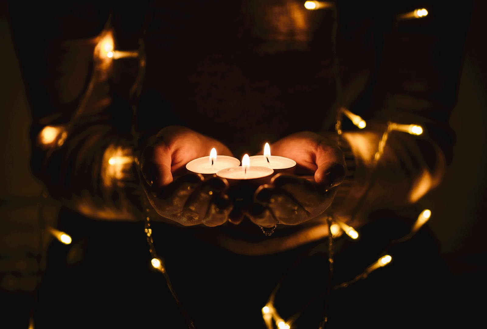 Three candles being held in the darkness | © Unsplash / Josh Boot