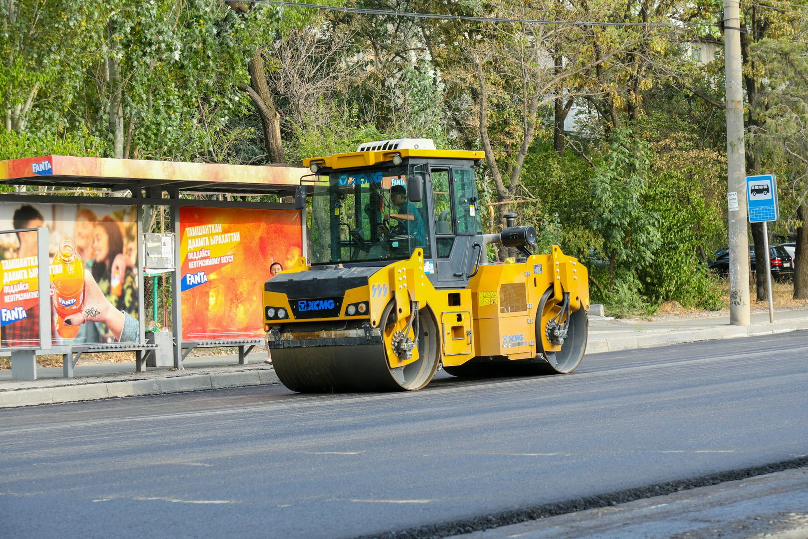 A road roller machine smoothing a new asphalt layer during road construction, with a focus on the machinery and street environment | © Unsplash / Collab Media