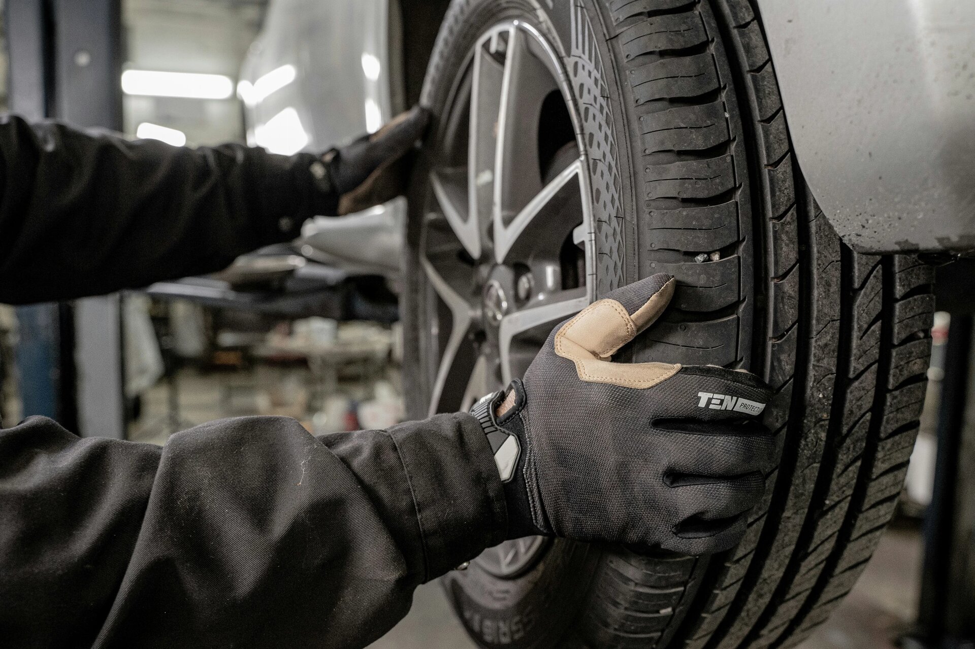 A mechanic changing tires with Ten Protection work gloves on.