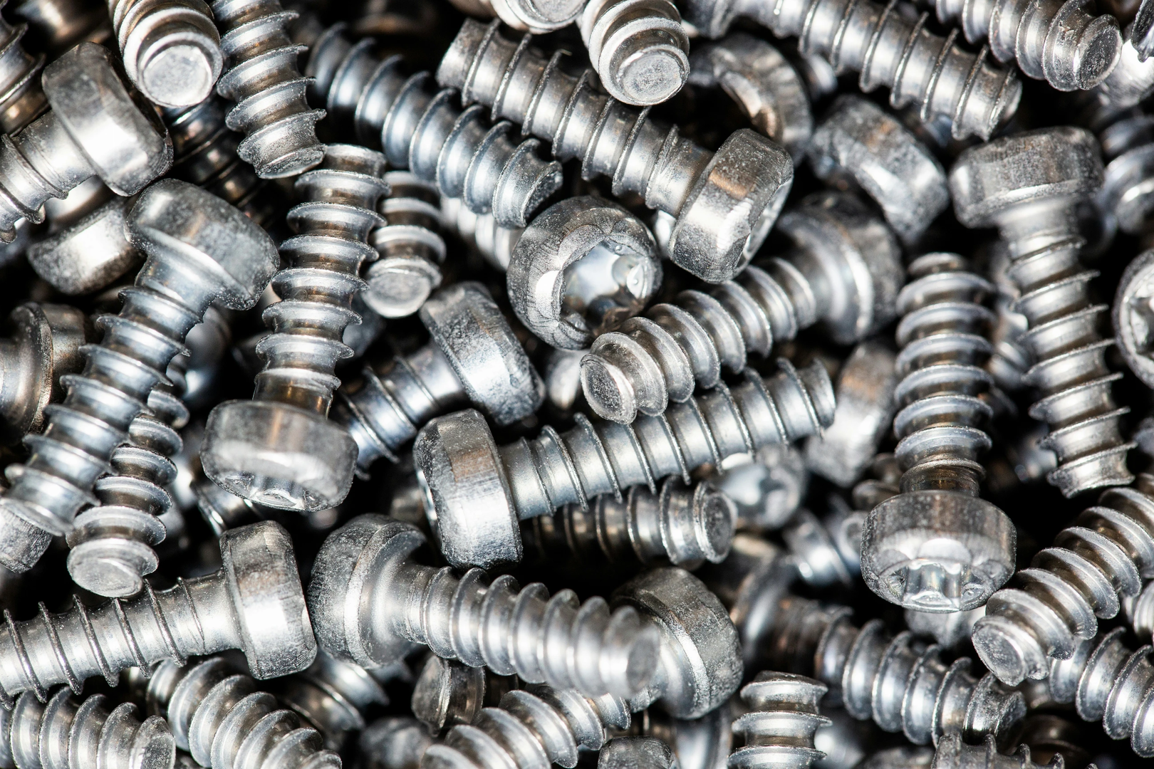 A huge arrenge of taping metal or iron screws, screws as a background, wallpaper or texture, industrial background and concept | © Unsplash / Simon Kadula