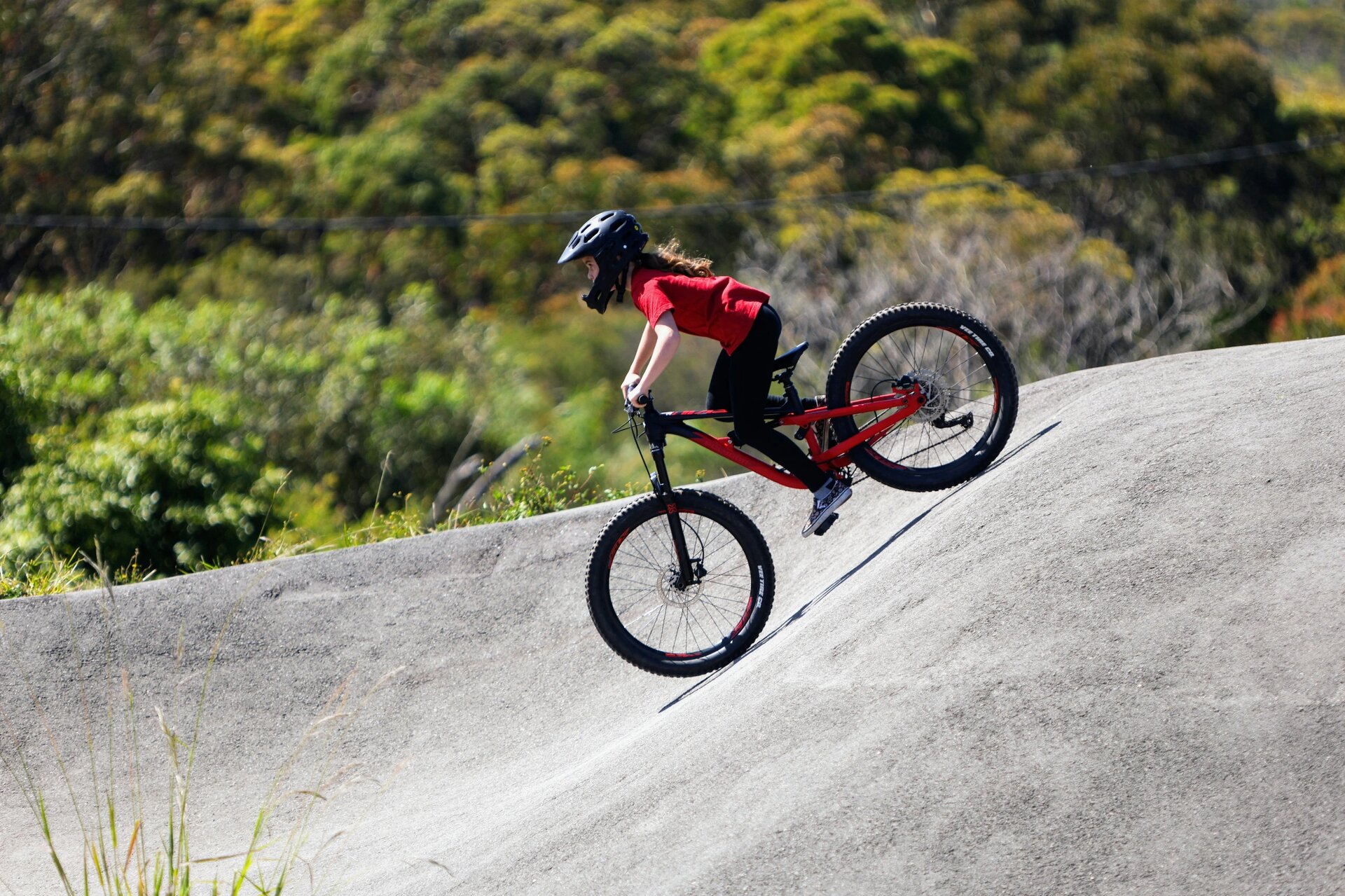 A girl riding a mountain bike on a pump track.