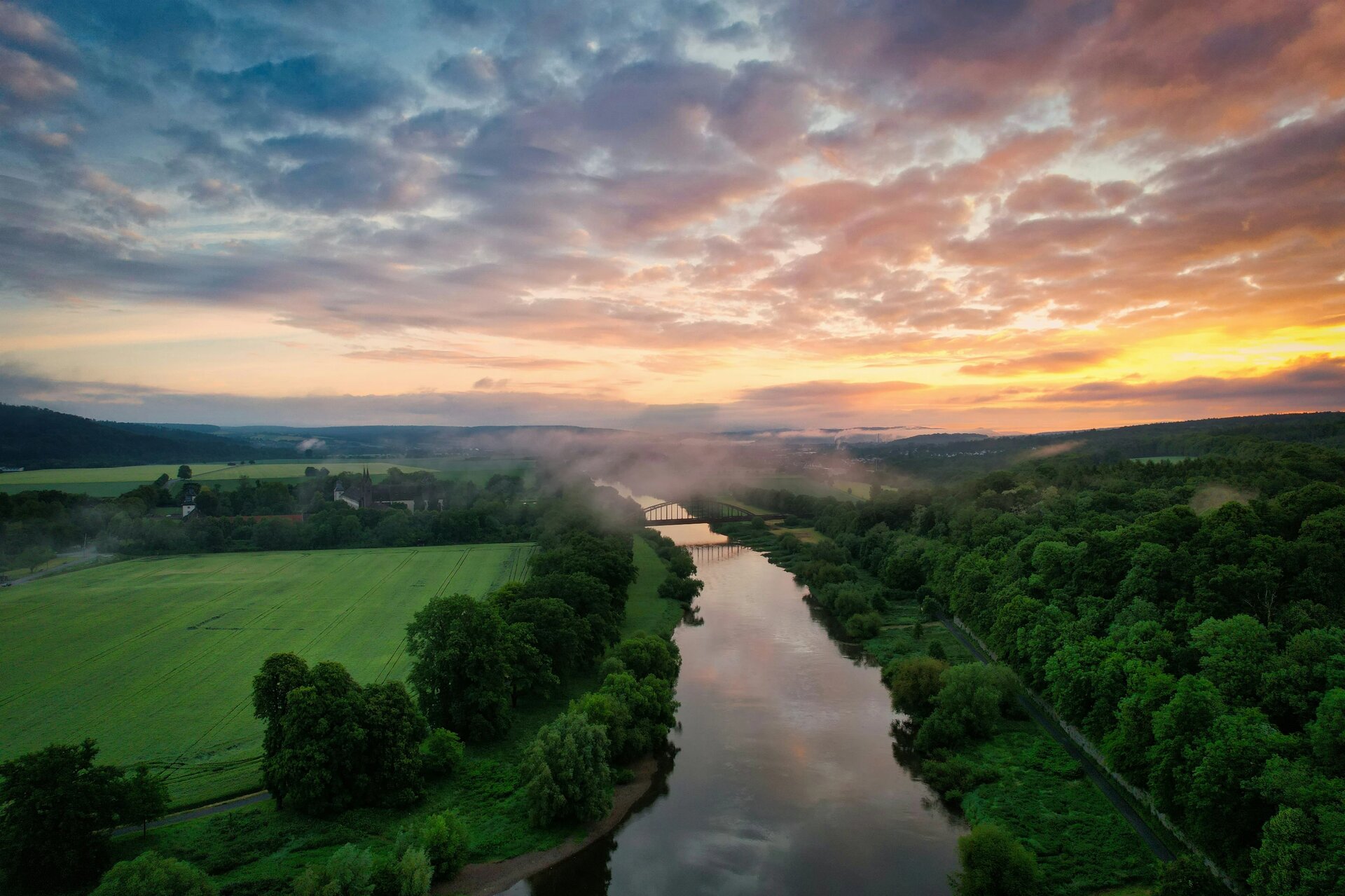 Die Eisenbahnbrücke bei Corvey im frühen Nebel gehüllt, im Hintergrund der wunderschöne Sonnenaufgang.